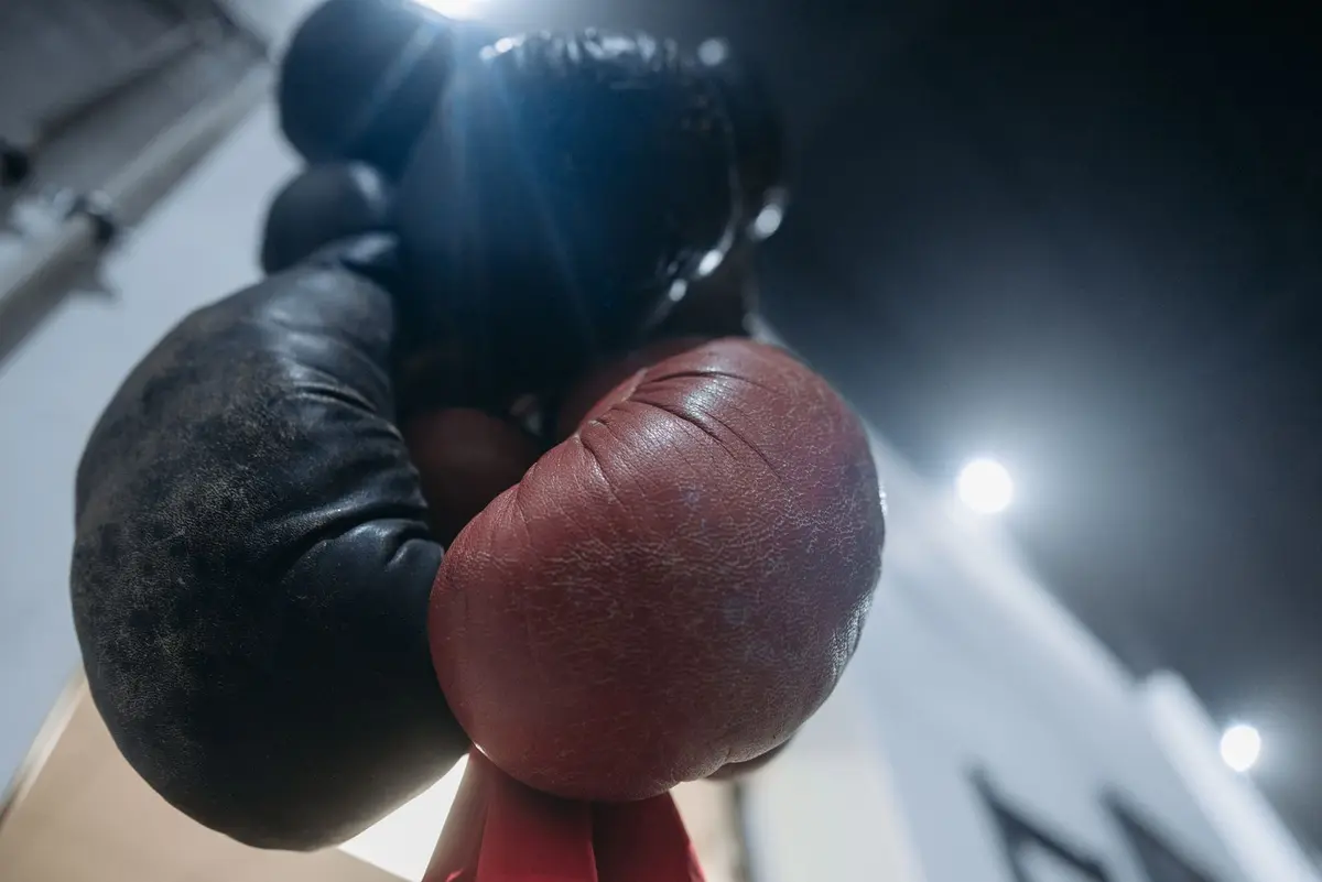 Zwei hängende Boxhandschuhe aus der Froschperspektive fotografiert, Nahaufnahme der Trefferflächen, keine Markenbeschriftung erkennbar